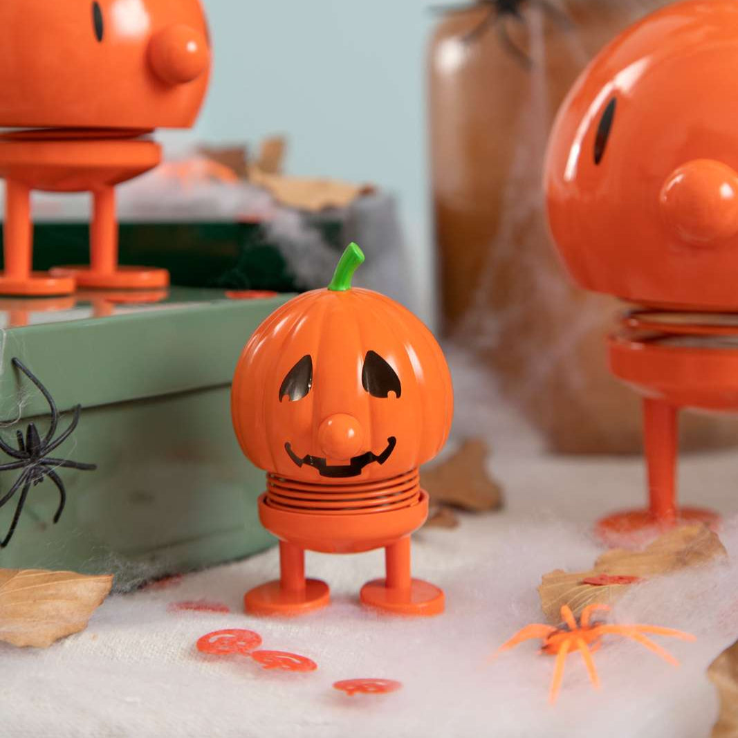 Three orange jack-o'-lantern-shaped lamps on a decorative surface with Halloween-themed elements.